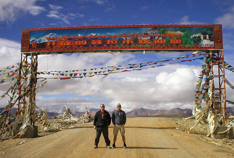 Guest posing in front of a welcome gate in Tibet